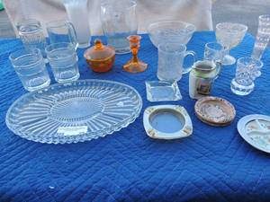 lot 89 image: Glass lot- 4 ashtrays various candle stick holders, orange glass  candy dish, drinking glasses