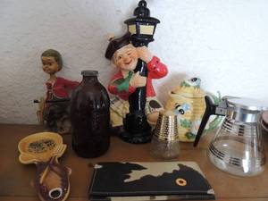 lot 29 image: Misc. lot-Avon fragrance bottle, 2 piece bee & flower dcor pot, Falstaff brewing beer bottle, Great Smokey Mountains spoon rest, coffee container, Hong Kong Boy doll, Korean price import glass Italian doll and tan and black wallet
