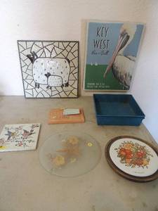 lot 117 image: 2 square turquois metal pans, Good wood hat pin holder  square bird tile, bread warmer with instructions, key west bar and grill sign 14x11,  12x12 wall tile Mother and baby sleeping Gabriella