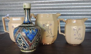 lot 136 image: 3 Tan  Pitchers W  Blue & Purple flowers,  gold trim around rim and handles  Stafford - ENGLAND   AND A  Turkish Blue and Black Design Bottle