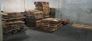 lot 128 image: Large lot of wooden pallets in assorted sizes as shown. Generous quantity