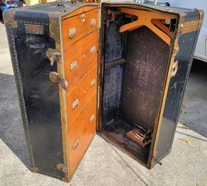 lot 147 image: ANTIQUE EARLY 1900S MENDEL-TRUNX WARDROBE STYLE STEAMER TRUNK WITH HANGERS AND IRON IN SOLID OVERALL CONDITION FOR ITS AGE AS SHOWN. MEASURES APPROX. 41.5 x 22 x 23. CHECK IT OUT