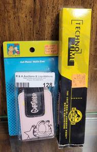 lot 128 image: COLLECTIBLE GARFIELD PHONE CASE AND JURASSIC PARK WATCH AS SHOWN.
