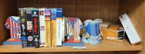 lot 443 image: SPORTS THEMED BOOKENDS, VHS VIDEOS, WOOD DESK ORGANIZER, SPRING SCALE, CANDLE WITH HOLDER AS SHOWN.
