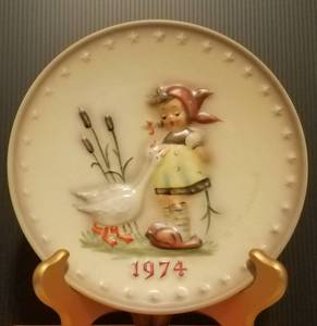 lot 28 image: 1974 M.J. HUMMEL PORCELAIN AND HAND PAINTED 4TH ANNUAL PLATE IN ITS ORIGINAL BOX AND IN EXCELLENT CONDITION AS SHOWN. MEASURES APPROX. 7.5 IN DIAMETER.