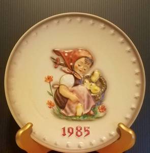 lot 39 image: 1985 M.J. HUMMEL PORCELAIN AND HAND PAINTED 15TH ANNUAL PLATE IN ITS ORIGINAL BOX AND IN EXCELLENT CONDITION AS SHOWN. MEASURES APPROX. 7.5 IN DIAMETER.
