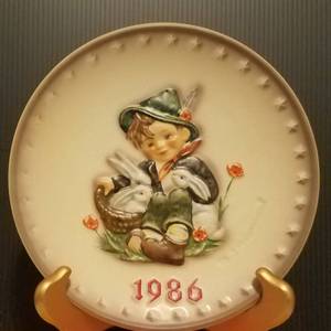 lot 40 image: 1986 M.J. HUMMEL PORCELAIN AND HAND PAINTED 16TH ANNUAL PLATE IN ITS ORIGINAL BOX AND IN EXCELLENT CONDITION AS SHOWN. MEASURES APPROX. 7.5 IN DIAMETER.