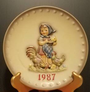 lot 41 image: 1987 M.J. HUMMEL PORCELAIN AND HAND PAINTED 17TH ANNUAL PLATE IN ITS ORIGINAL BOX AND IN EXCELLENT CONDITION AS SHOWN. MEASURES APPROX. 7.5 IN DIAMETER.
