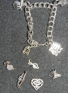 lot 335 image: Charm bracelet- #1 grad, french horn x 2, music note, Ice skate, heart, trumpet