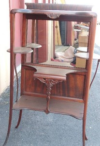 lot 2 image: Victorian Art Nouveau dumbwaiter. Panelled Walnut. Intricate carved and with cabriole slender legs,  oval shelving x 2 tiers has mirror on back 47x24x14  Circa about 1910