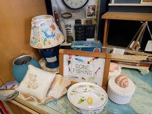 lot 671 image: FRAMED GONE FISHING NEEDLEPOINT, CANDLE JAR WITH MERMAID THEMED CERAMIC BASE AND SHADE, SEA SHELL TOPPED TRINKET BOXES AND MORE AS SHOWN.