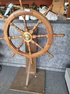 lot 723 image: VINTAGE ORIGINAL HARDWOOD SHIP WHEEL WITH BRASS HUB MOUNTED ON HAND-MADE STAND AS SHOWN. WHEEL MEASURES APPROX. 42 IN DIAMETER AND IS IN GREAT OVERALL CONDITION FOR ITS AGE.