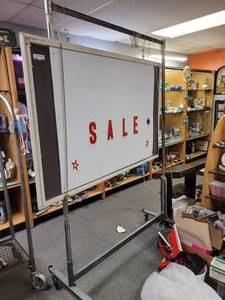 lot 885 image: METAL CLOTHING RACK ON WHEELS WITH A BOARDSIGN AS SHOWN.