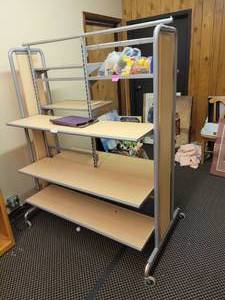 lot 984 image: DOUBLE SIDED METAL FRAME WITH WOOD SHELVES DISPLAY UNIT ON ROLLERS IN STYLECOLOR SHOWN. CONTENTS SHOWN NOT INCLUDED