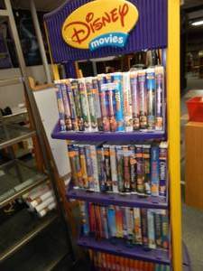lot 1133 image: DISNEY MOVIES DISPLAY SHELVING UNIT ON WHEELS AS SHOWN.CONTENTS SHOWN NOT INCLUDED (DELAYED PICK UP BETWEEN 200 PM AND 400 PM)