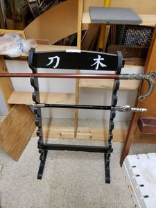 lot 1024 image: WOOD RACK WITH TWO SWORDS IN STYLES SHOWN. CHECK THESE OUT