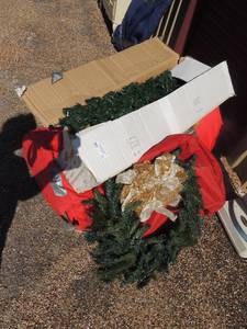 lot 11 image: Christmas lot- 7 ft. tree in red bag, 42 lighted porch tree. Green door wreath with silver bow in red wreath bag.