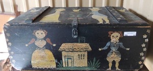 lot 94 image: Folk Art doll chest. Black, has latch for lock painted dolls and house on top 33Lx 16D 13T