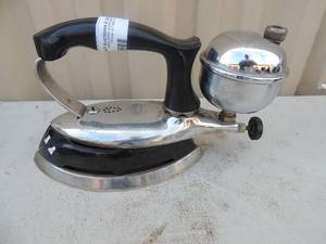 lot 180 image: Metal iron with handle  has gassteam chamber marked coleman instant life model #609 made in USA 8x4x6