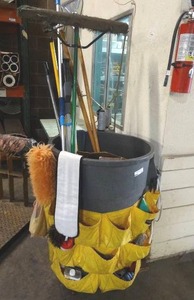lot 224 image: Janitorial supplies. Includes trash can w rolling base, apron w cleaning accessories, brooms, sweeping pads and more