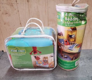 lot 49 image: Sesame Street Toddler Bedding Sets.  Both are 4-piece bedding sets.  Never opened.