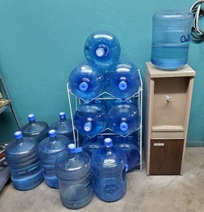lot 197 image: Water cooler and 14 5-gallon jugs (some full and unopened).  7 jugs are full.