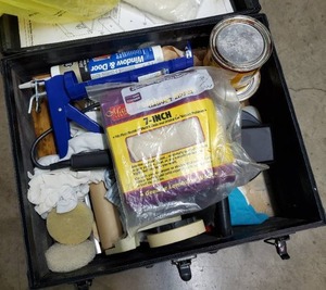 lot 210 image: Atrium black box with stains, caulk & caulk gun, tape and polishing pads.