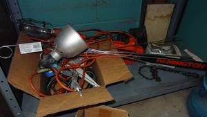 lot 199 image: Contents of bottom shelf.  Includes box of task lights, extension cords, Remington chainsaw and bolts