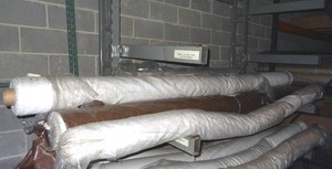 lot 321 image: Long fabric rolls on middle rack only.  White fabrics w various patterns.