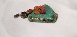 lot 767 image: A large Mojave Green or Lime Green turquoise pendant with carved carnelian kissing boy and girl accent. O-ring is unmarked but probably sterling.