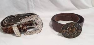 lot 783 image: Leather belts. Includes Coldwater Creek belt with brass colored buckle with chip bead stone accents (Size L) and printed cowhide or pony hide leather belt with crystal studded buckle and fleur de Lis accents. (Missing a few crystals, some patina to metal)