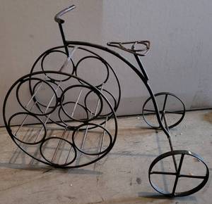 lot 34 image: WROUGHT IRON STYLE TRICYCLE WINE RACK AS SHOWN. APPROX. 21 L x 16.5 H x 12.75 D.