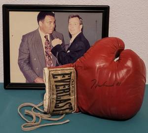 lot 52 image: EVERLAST BOXING GLOVE SIGNED BY THE LATE MUHAMMAD ALI AS SHOWN. THE PICTURE SHOWS THE SELLER POSING WITH THE BOXER WHEN IT WAS SIGNED. PICTURE NOT INCLUDED.