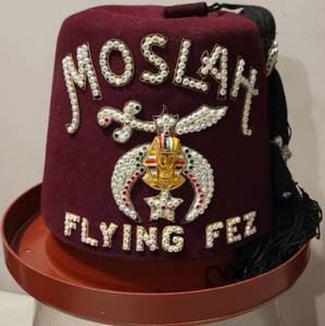 lot 76 image: SHRINERS MOSLAH FLYING FEZ HAT WITH HOLDER IN STYLE, COLOR, AND CONDITION SHOWN.