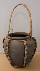 lot 15 image: CLAY PLANTER WITH WICKERRATTAN STYLE ACCENTS IN STYLE, COLOR, AND CONDITION SHOWN.