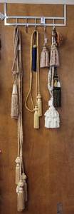 lot 67 image: OVER-THE-DOOR METAL HANGER WITH ASSORTED DECORATIVE TASSELS AS SHOWN.