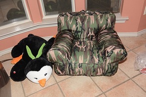 lot 99 image: Camouflage kid sitting chair and penguin stuffed animal