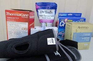 lot 214 image: First aid lot- Knee and hand braces, band aids, Cryolax cold Pac, thermal care heat wrap, Foot soak, Averno bath treatment