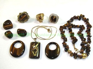 lot 566 image: Tiger Eye Grouping. Includes an 18K Gold Electroplate ring Size 6.75, 2 fashion Tiger Eye rings, a Tiger Eye Necklace and assorted Beads. Also includes a Tiger Eye Gold Filled Pendant on chain with red blue and white prong set stones. No markings.