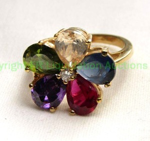 lot 681 image: Multi Gemstone Flower ring. Includes Amethyst, Sapphire, Ruby plus. Gold Tone No markings. Center stone is not diamond. Size 6.5 Gemstones tested