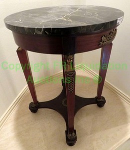lot 653 image: Vintage Colbys Empire Egyptian Revival round mahogany table with black marble fitted top and ormolu mounts. 24 x 31