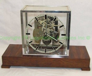 lot 397 image: Unique industrial theme minimalist skeleton mantle clock in glass case, wood base No markings, 9.5 tall x 14.5 wide