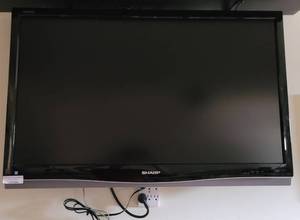 lot 344 image: SHARP FLAT SCREEN TV WITH REMOTE CONTROL AS SHOWN. BUYER IS RESPONSIBLE FOR PROPERLY REMOVING FROM WALL.