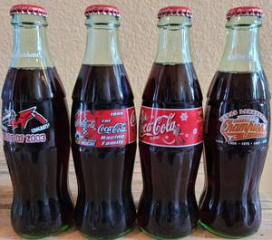 lot 245 image: LOT OF 4 COCA-COLA UNOPENED COMMEMORATIVE COLLECTIBLE BOTTLES AS SHOWN.