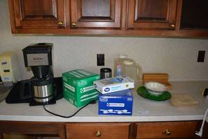lot 9 image: Contents on Counter Iced Tea Pot, Bunn Coffee Pot, Plasticware and Plates