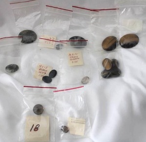 lot 510 image: Gemstone cabochons in individual packages. Varying sizes and materials. Includes Black Onyx, Tiger Eye, Moss Agate, Obsidian Snowflake, Smokey Quartz, Plus