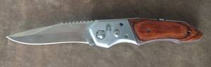 lot 133 image: Two Pocket Knives, one with Strong Spring action, the blade snaps into place, Stainless steel, wood handle, heavy, 8.75 inches total length the blade is 3.75 inches long, missing one screw, a Buck #425 pocket knife. (One Money)