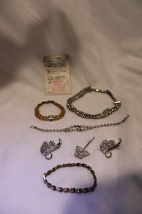 lot 435 image: Bling jewelry selection. Includes a rhinestone necklacebracelet set, (2) additional bracelets, and (2) scroll pins. Also includes a Lindenworld CZ in original pouch.