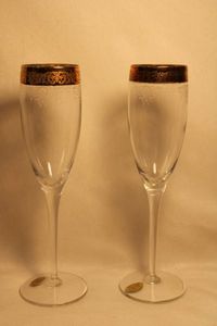 lot 361 image: Set2 - Italian Cellini blown crystal champagne flutes with 24K gold accent rim and etching. Hand decorated. Made in Italy. Both have original labels. 9H No chips.