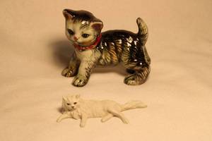 lot 325 image: Cat duo. Includes Camille Naudot (1882-1938,France) porcelain Tabby kitten figure and Capodimonte Creazioni Bindi lounging cat figure. Label on bottom with Capodimonte N. Residual minimal paint loss around collar.